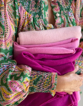 Woman holding a bundle of Kasmiri Cashmere Travel Wraps in Shades of Pinkd