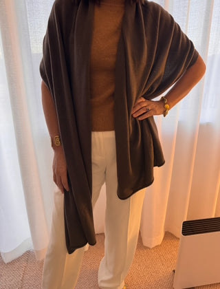 woman wears a neutral top with a brown cchocolate travel wrap over her shoulders
