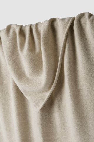 Close-up of beige wheat coloured cashmere travel wrap shawl with a soft texture that is knitted with a rolled edge