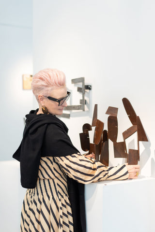 Sophie Vander wearing a black Kasmiri cashmere wrap stands next to a scultpure by artist Caroline Duffy. 
