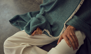 Woman is wrapped in an emerald green cashmere throw with white fringes | KASMIRI throw blankets online