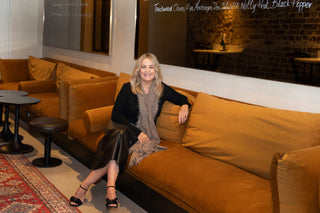 woman on an amber velvet couch in a bar wearing a Kasmiri undyed cashmere shawl. 