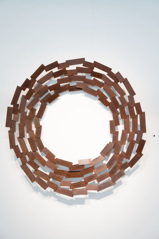 Circular wall art made of interlocking scrap metal pieces by artist Caroline Duffy on a white background