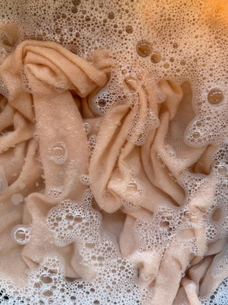 Pink cashmere wrap in water with suds