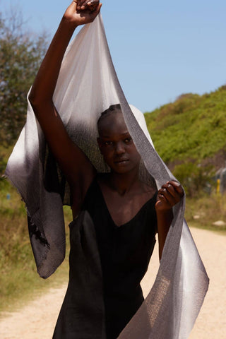 Person holding a white scarf over their head with a natural background