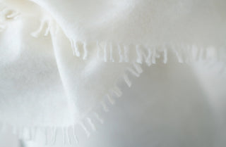 Close-up of a soft white cashmere shawl with fringing