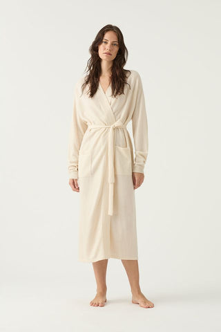 Woman wearing a cream-colored cashmere robe tied at the front and showing two patch pockets