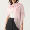 A cashmere scarf in blush pink drapes around the shoulders. The oversized square scarf has a whimsical, cloud like texture